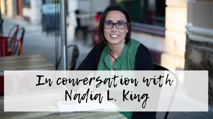 Image of Nadia L King sitting at a outdoor cafe table. Overlaying the image are the words In conversation with Nadia L. King